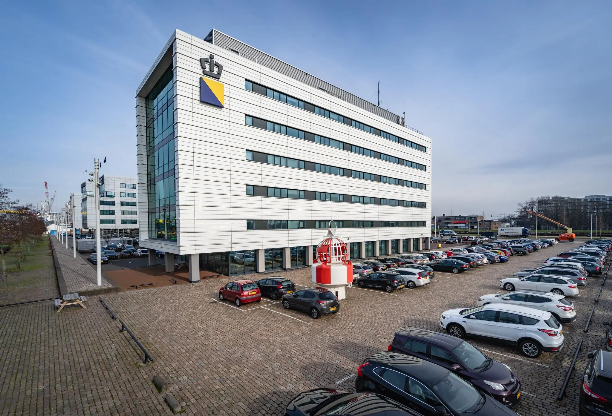 Kantoorgebouw aan de Waalhaven-Oostzijde in Rotterdam met naastgelegen parkeerterrein vol auto’s.